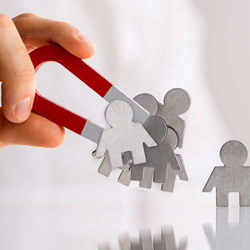 Mão segurando um ímã atraindo figuras humanas metálicas, simbolizando captação, organização e gestão de contatos.