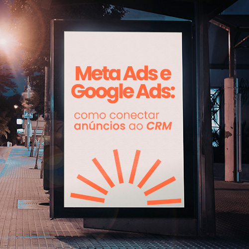 Painel publicitário iluminado em ponto de ônibus à noite, com rua urbana, árvores e rastros de luz dos carros em movimento.