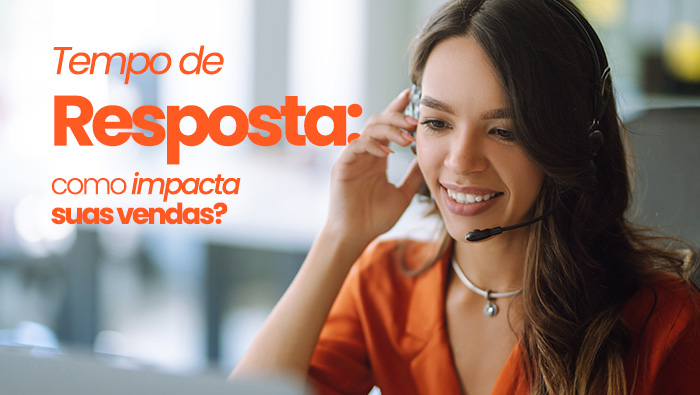 Atendente com headset sorri enquanto fala ao computador, realizando atendimento ao cliente em ambiente de trabalho.