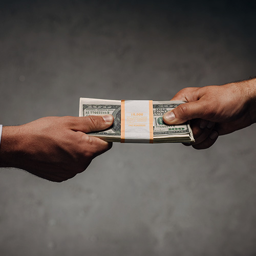 Duas pessoas trocando um maço de dinheiro, representando negociação, vendas e fechamento de negócios.