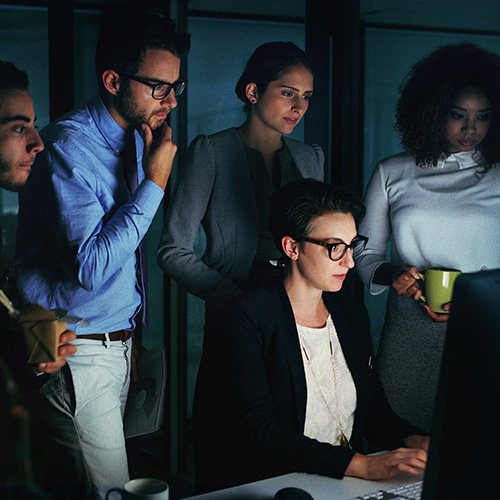 Equipe de profissionais analisando informações no computador em ambiente corporativo, representando gestão colaborativa de leads e tomada de decisões.