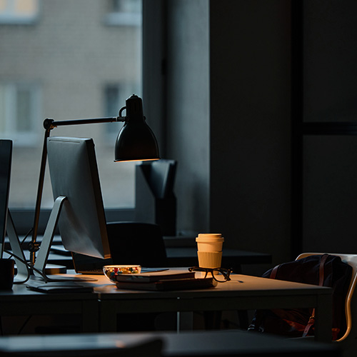 Mesa de escritório com computador e iluminação baixa, representando organização, rotina de trabalho e gestão de leads.