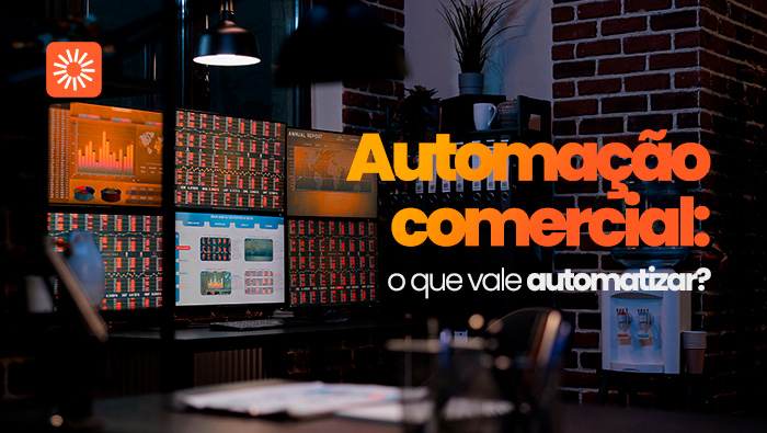 Escritório com mesa de trabalho, vários monitores exibindo gráficos e painéis de dados, estante com pastas, dispenser de água e iluminação em ambiente interno.